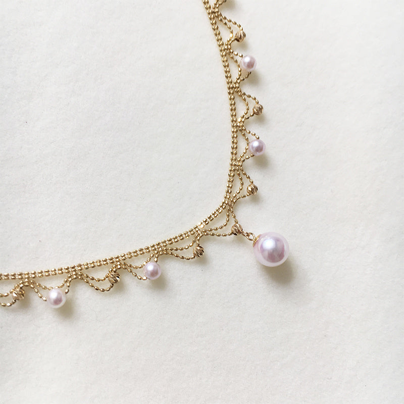 Gold chain necklace with pearls on a light background