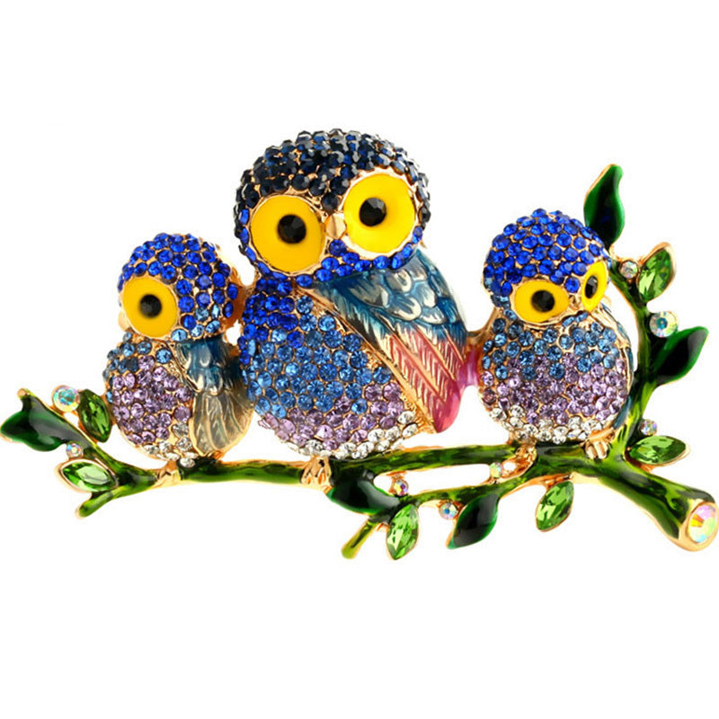 Colorful owl brooches on a branch with a white background