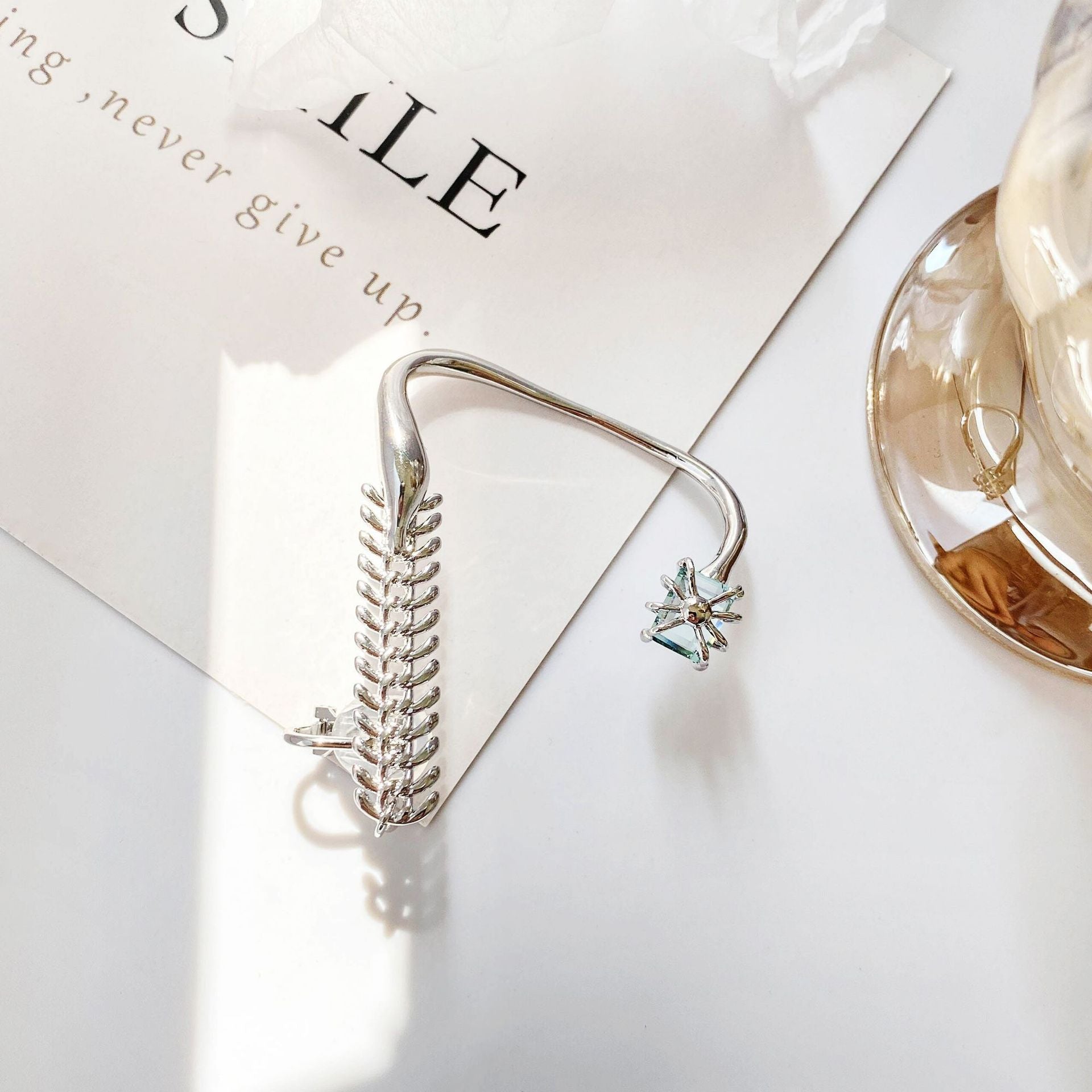 Silver hair clip with decorative elements on a white surface
