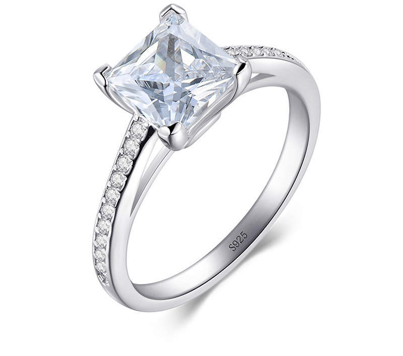 Silver ring with a large diamond and smaller diamonds on the band against a white background