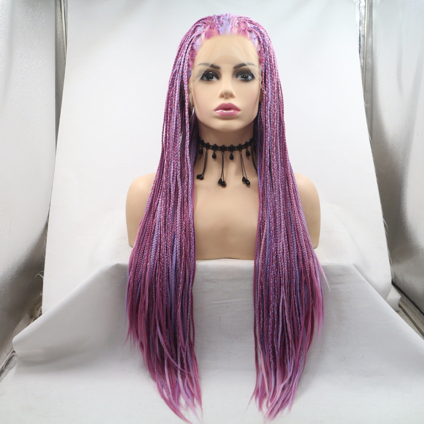 Mannequin head with a purple and pink braided wig on a white background