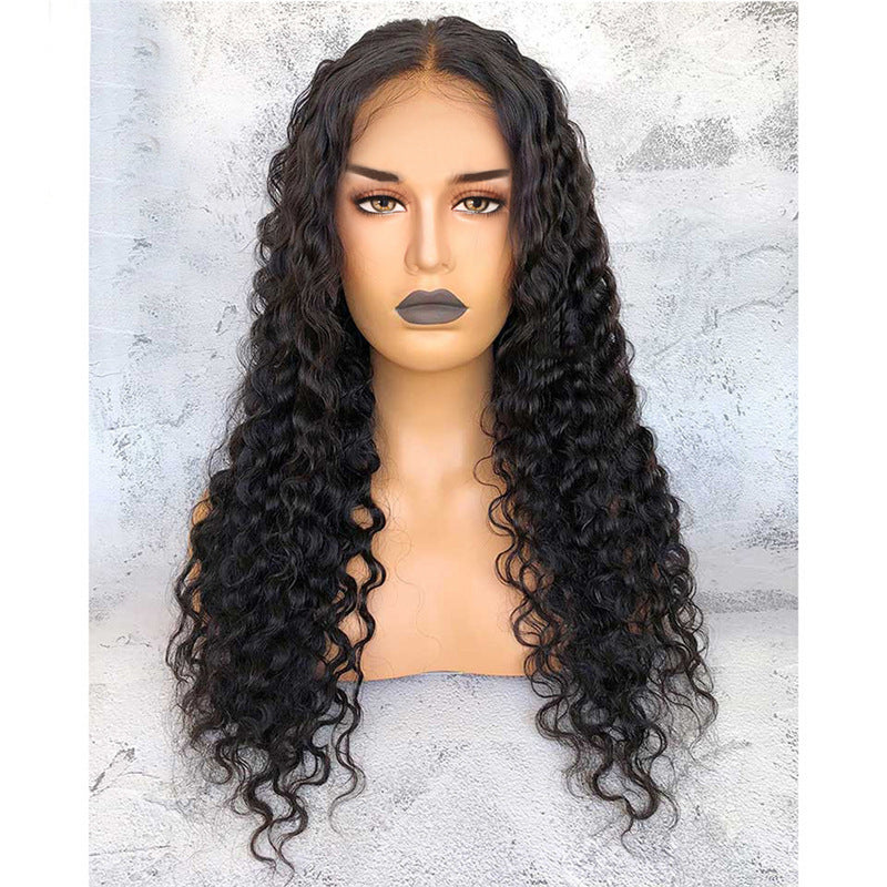 Black curly wig on a mannequin head against a textured gray background