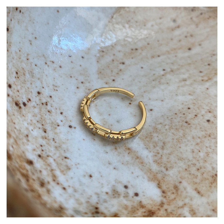 Gold hoop earring on a textured beige surface