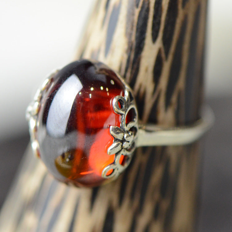 Close-up of a silver ring with a red gemstone on a textured surface