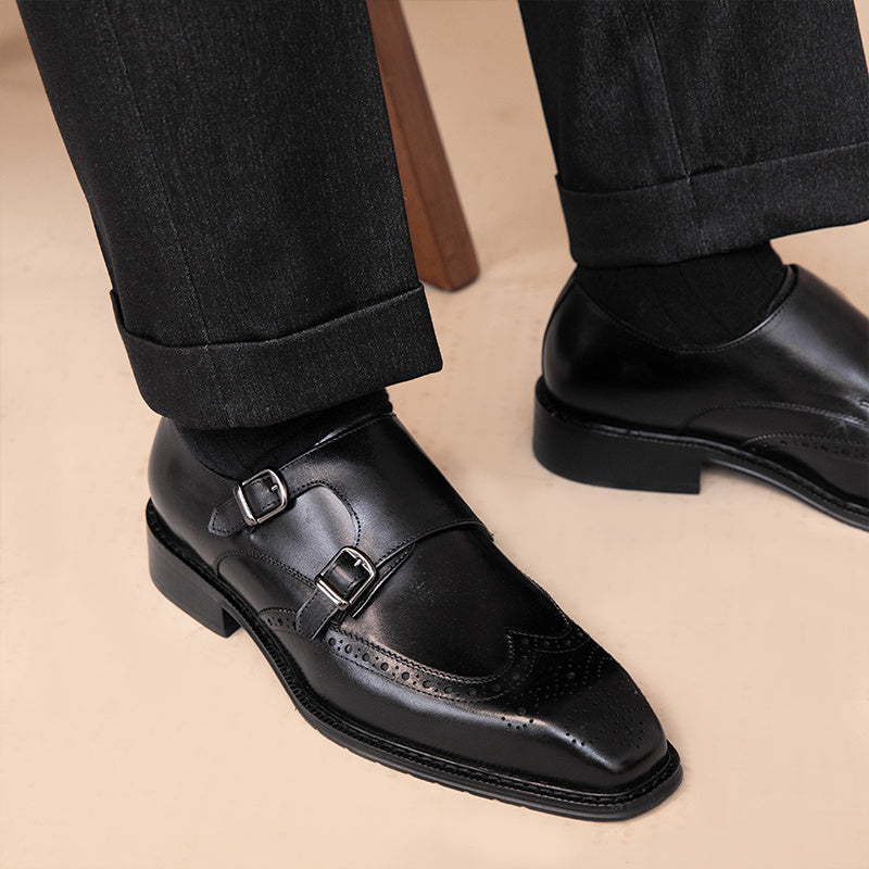 Black dress shoes with buckles worn with black pants on a beige background