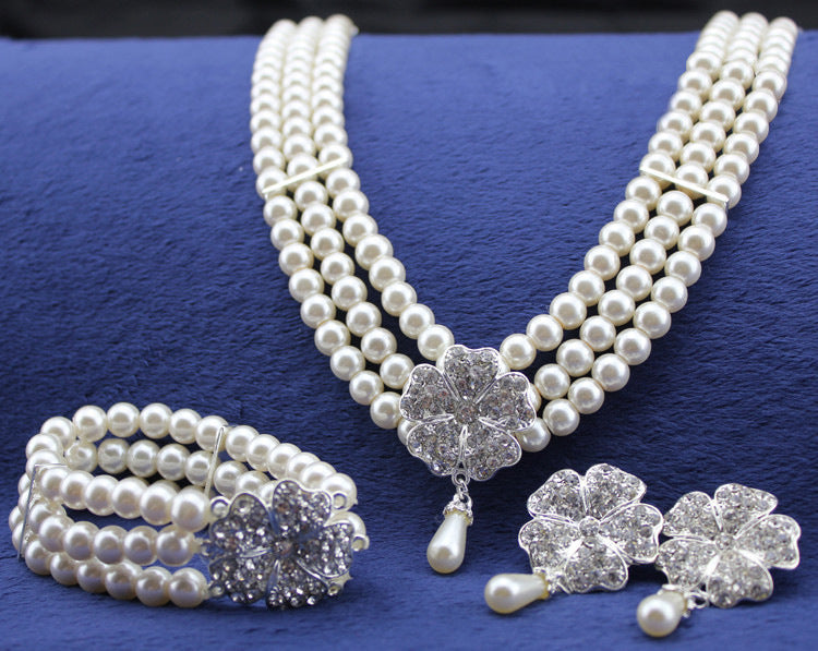 Pearl necklace, bracelet, and earrings on a blue background