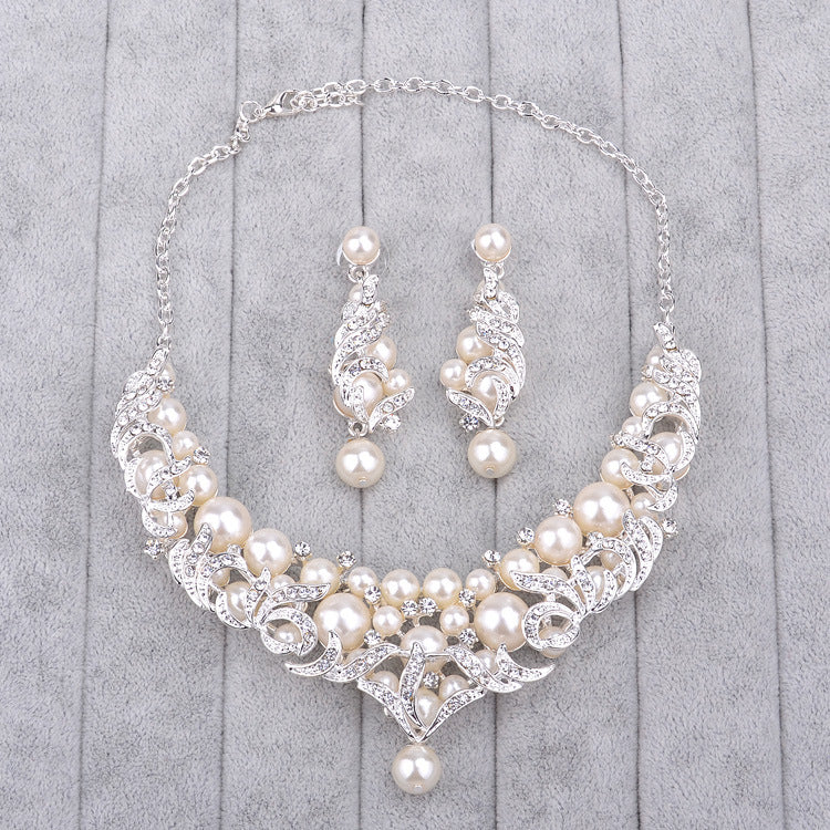 Pearl necklace and earrings set on a gray wooden surface