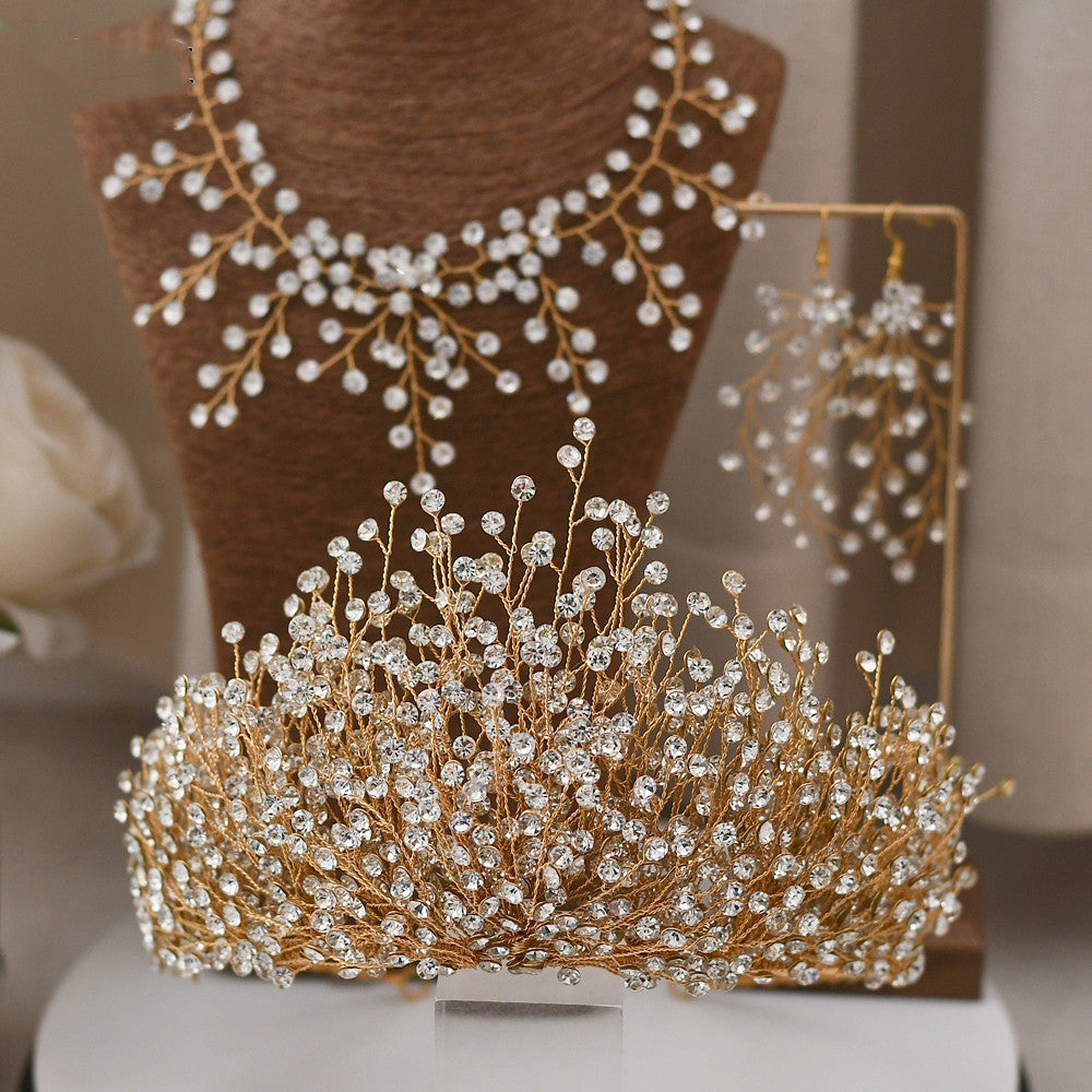 Gold tiara with crystal embellishments on a stand, with a blurred background