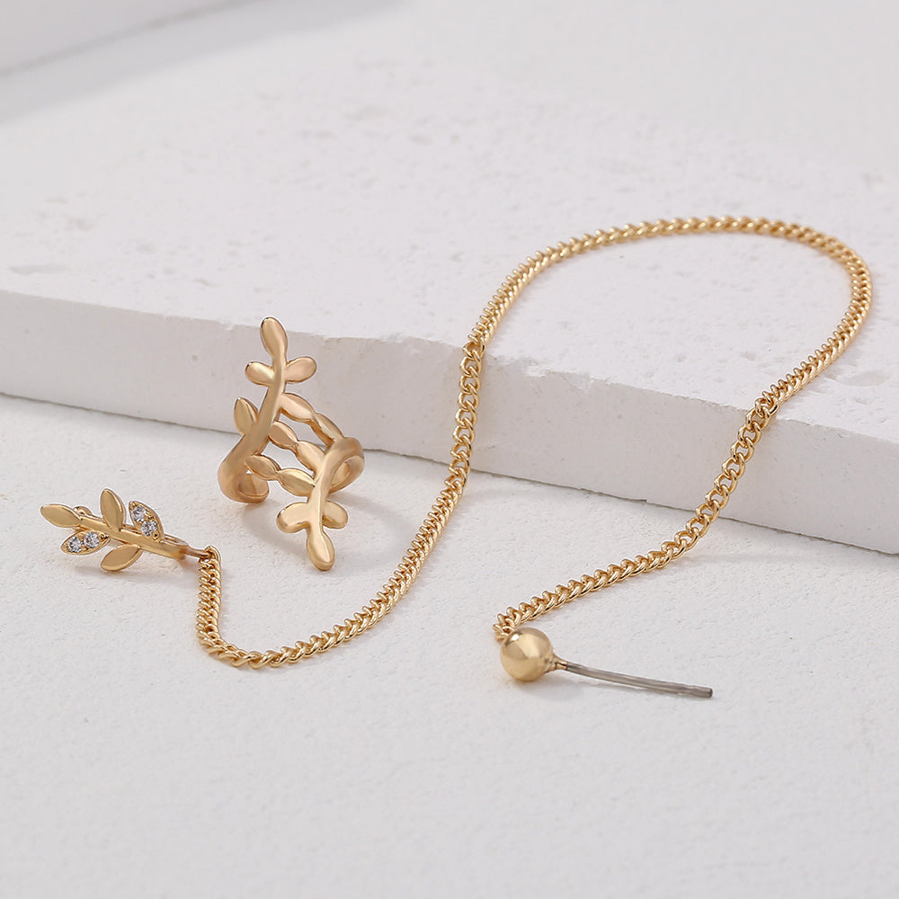 Gold jewelry set with chain and leaf design on a light background