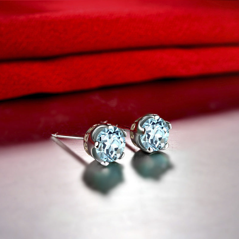 Silver earrings with clear gemstones on a red fabric background