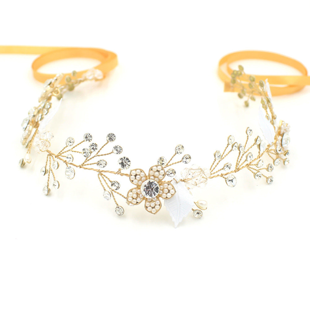 Gold headband with floral design and rhinestones on a white background