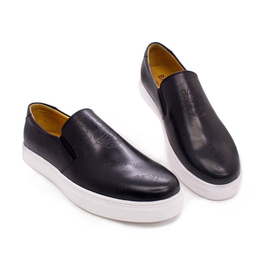 Pair of black slip-on shoes with white soles on a white background