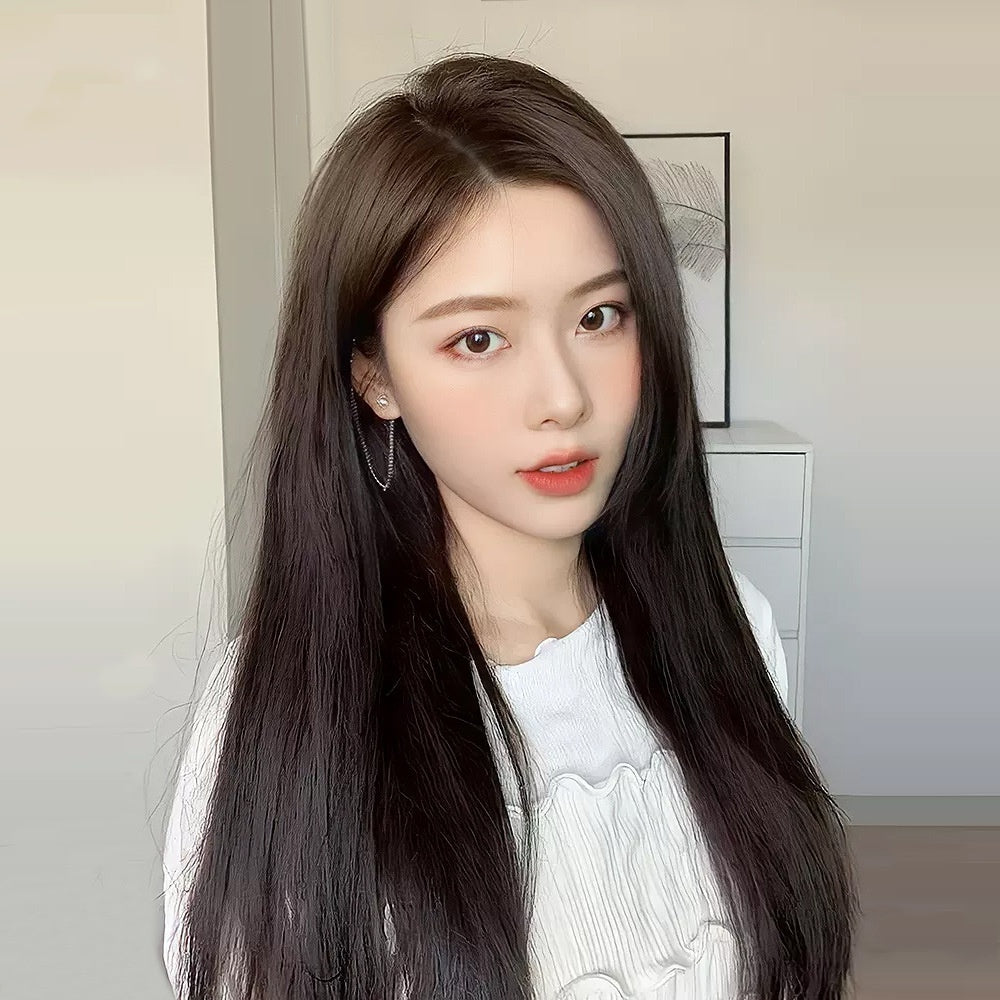 Woman with long dark hair wearing a white top in a neutral setting