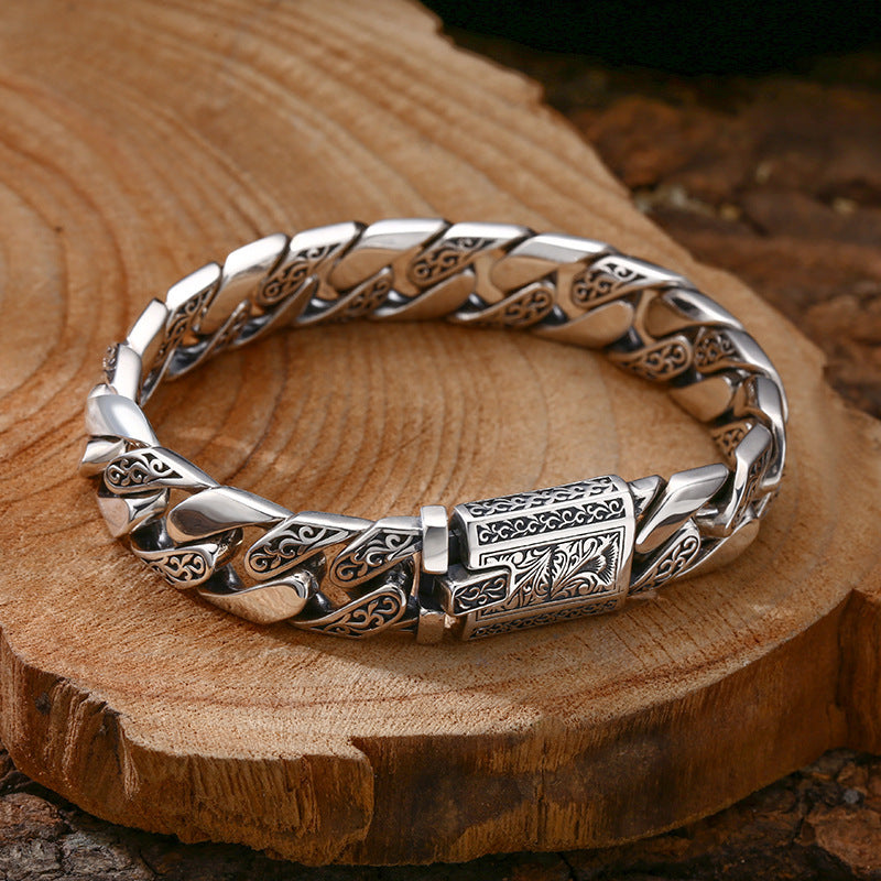 Silver bracelet with intricate designs on a wooden surface