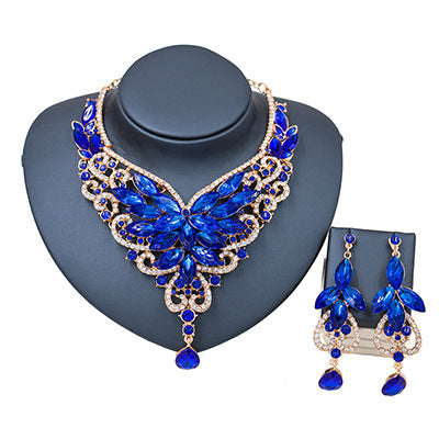 Blue butterfly necklace and earrings set on a gray stand with a white background