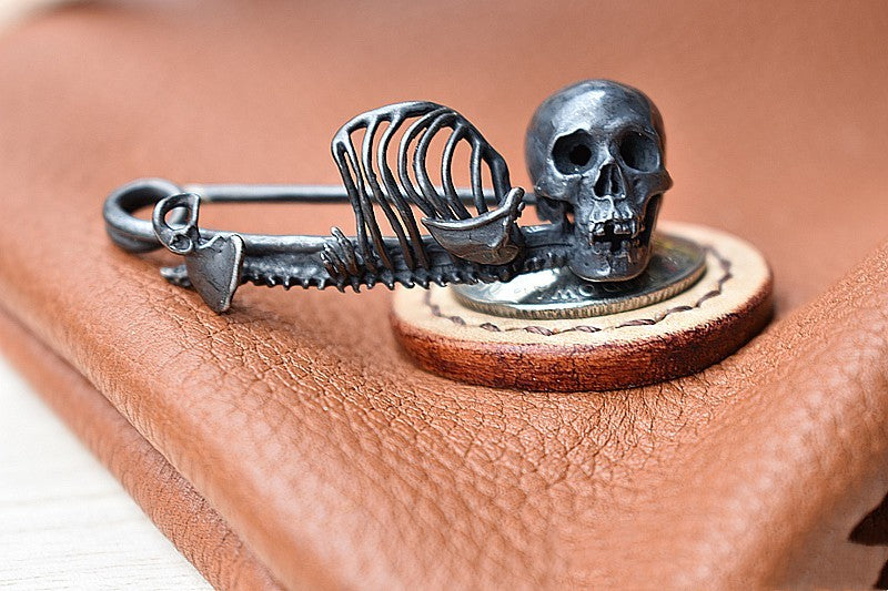 Silver skeleton key and skull design on a leather surface