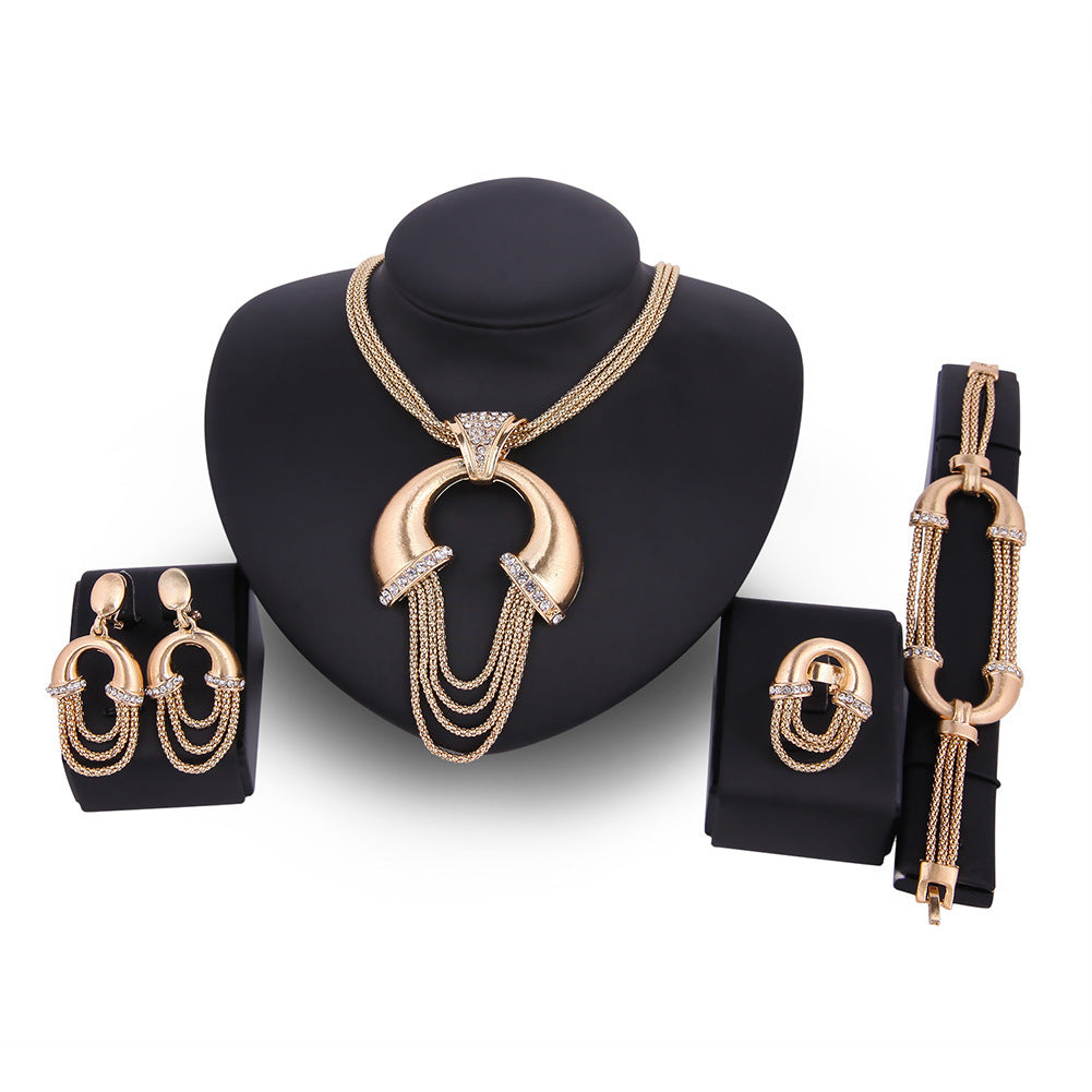 Gold jewelry set including necklace, earrings, and bracelet on a black stand with a white background.