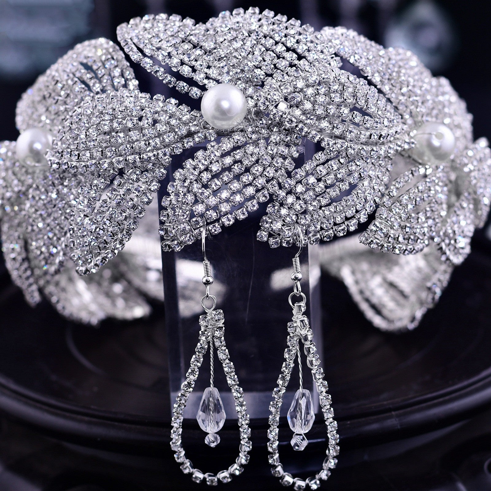 Silver headpiece with pearls and matching earrings on a dark background
