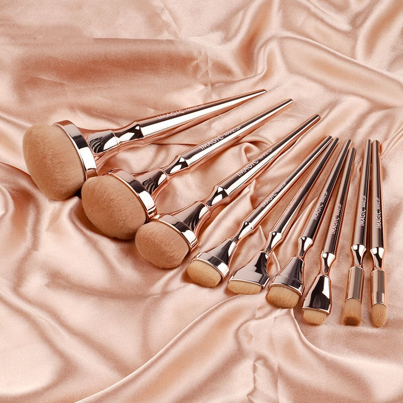 Set of rose gold makeup brushes on a pink satin background
