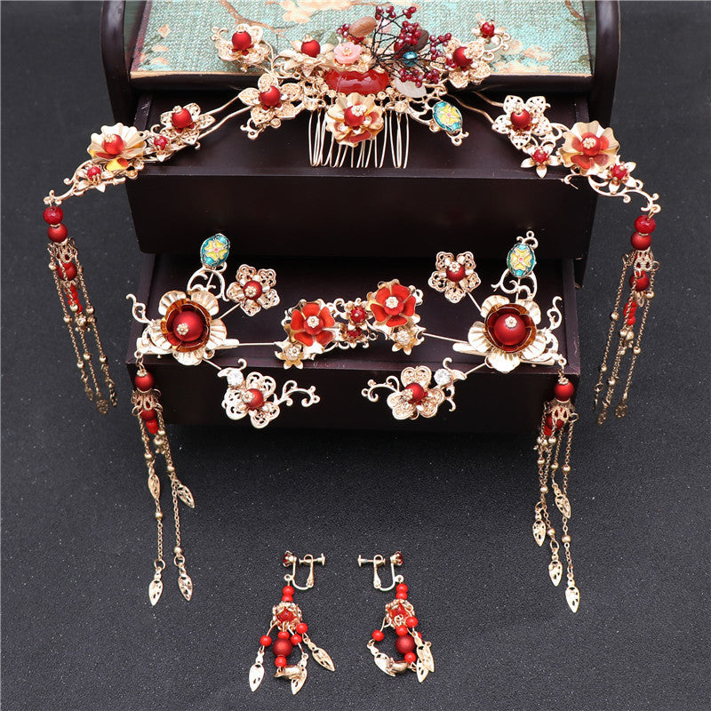 Ornate hairpiece and earrings with red and gold accents on a dark background