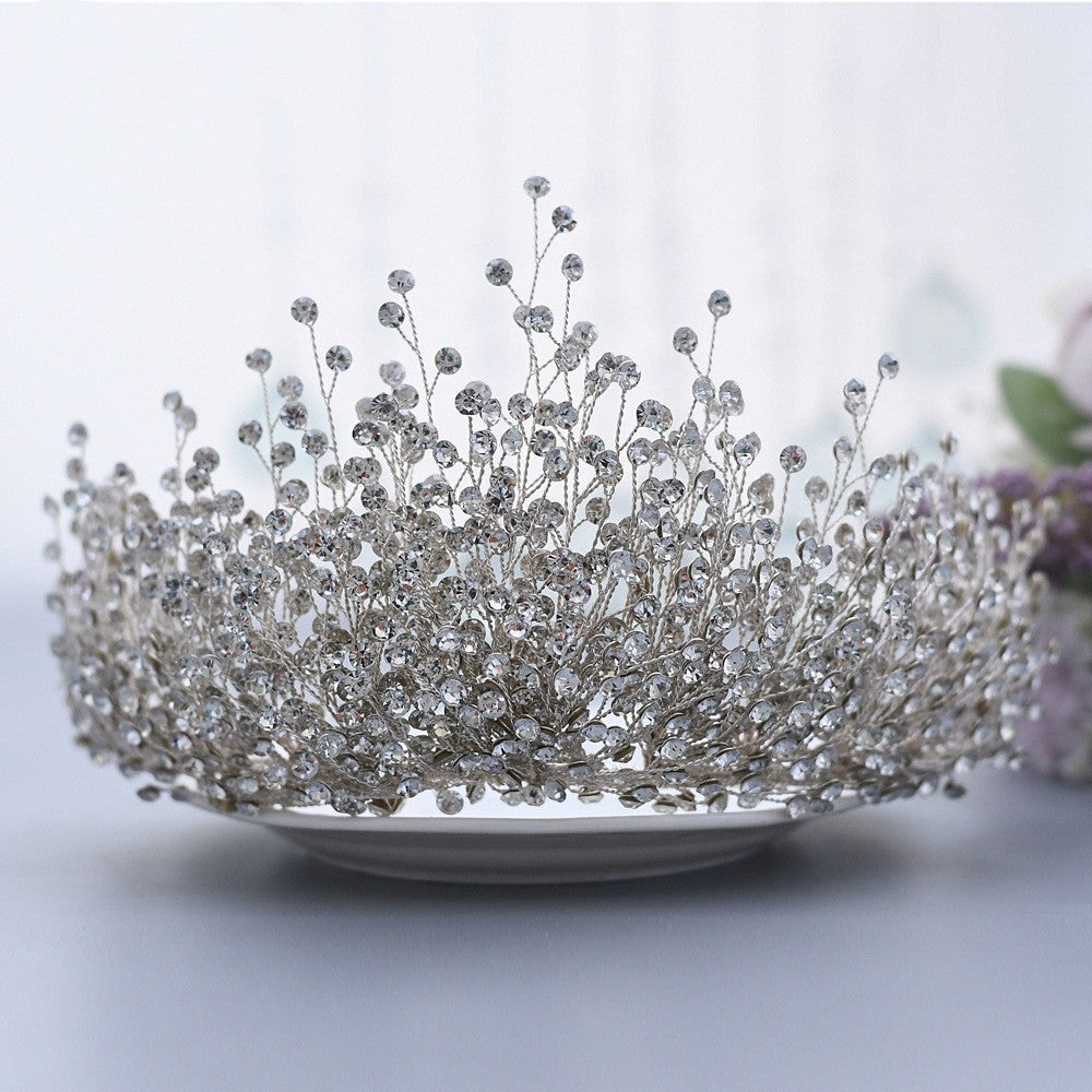 Silver tiara with intricate design on a white plate against a light background