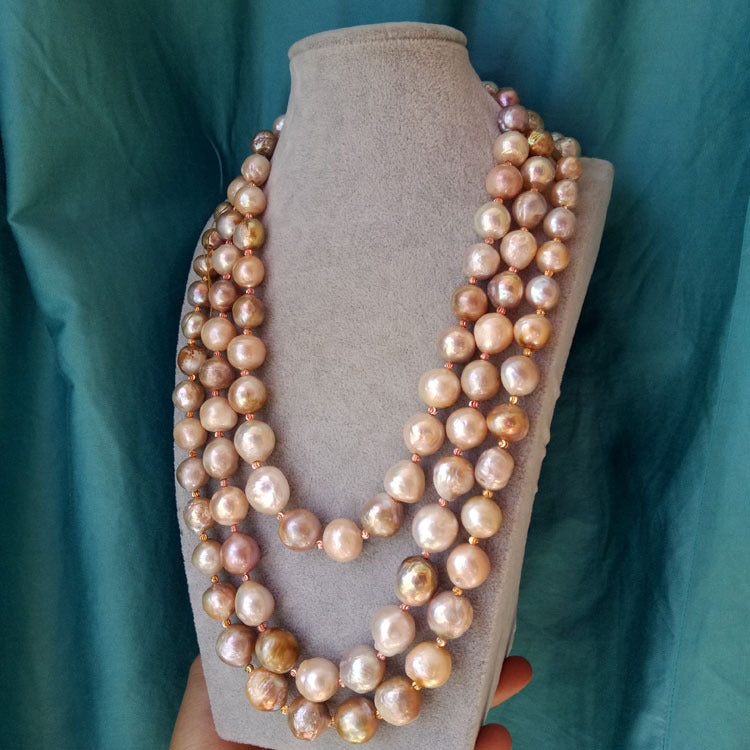 Pearl necklace on a mannequin bust against a teal background
