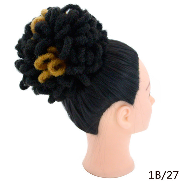 Mannequin head with black and yellow hair bun accessory on a white background