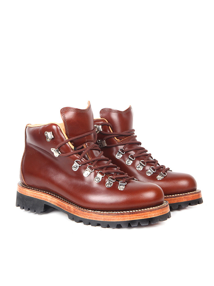 Pair of brown leather boots with orange soles on a white background