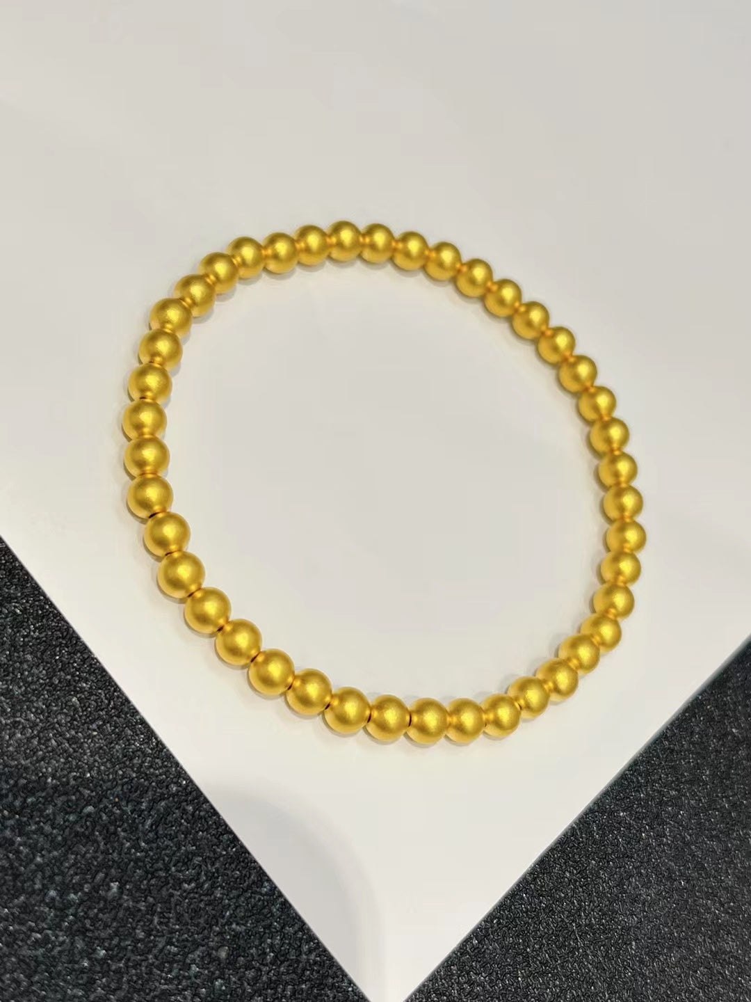 Gold beaded necklace on a white and black textured background
