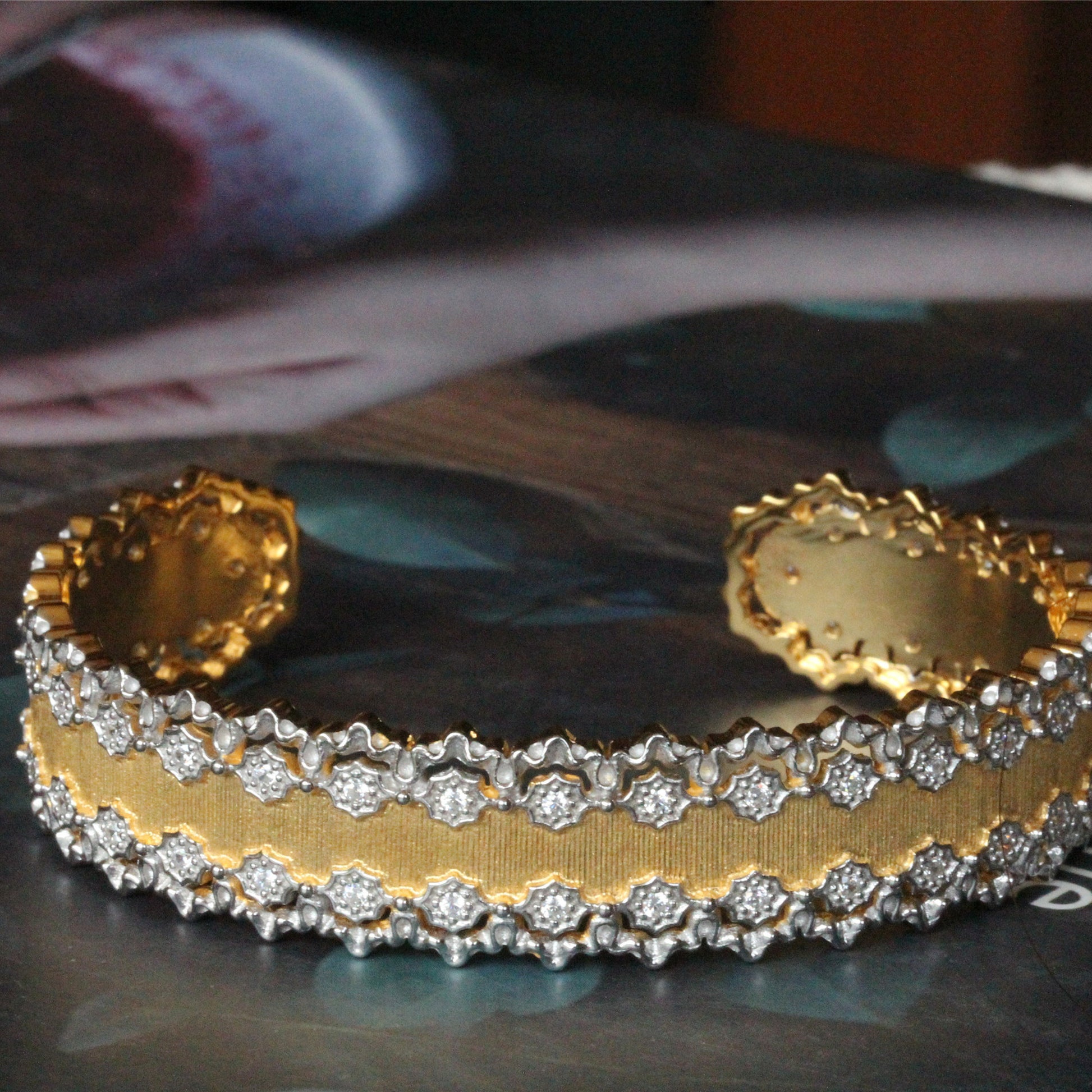 Gold bracelet with diamond accents on a reflective surface