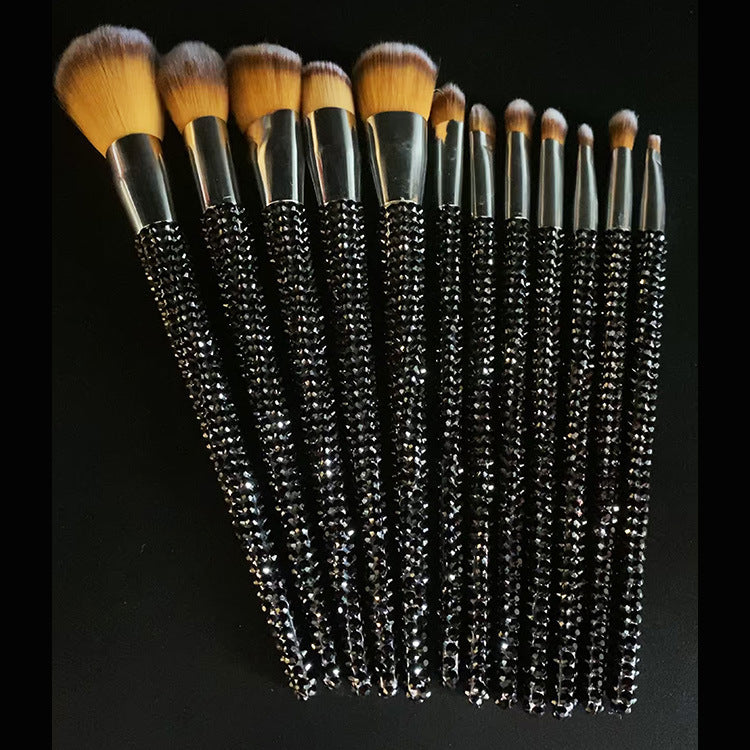 Set of makeup brushes with black rhinestone handles on a black background