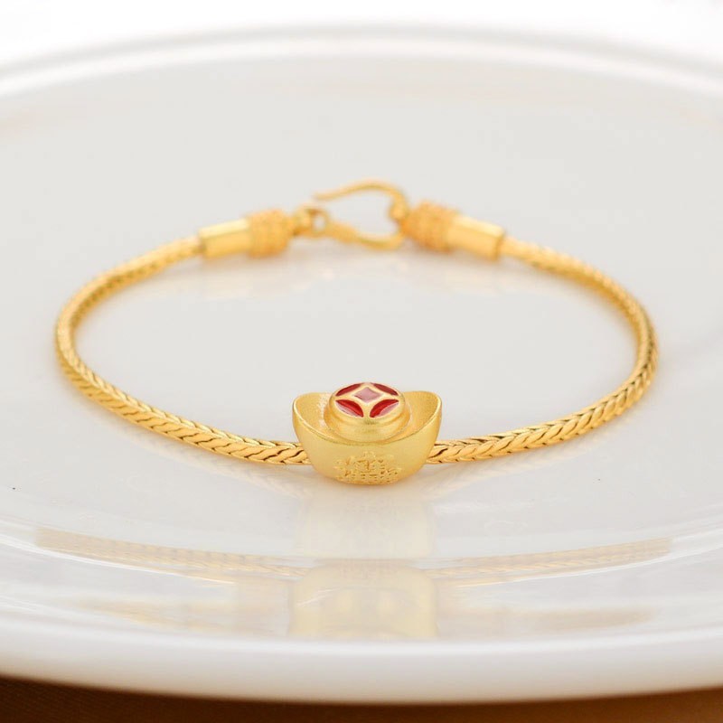 Gold bracelet with a red gemstone on a white plate