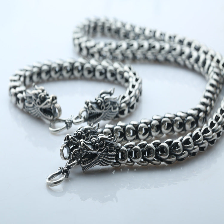 Silver chain necklace with dragon clasp on a light background