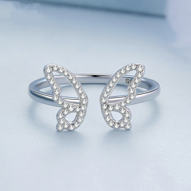 Silver butterfly-shaped ring on a light blue background