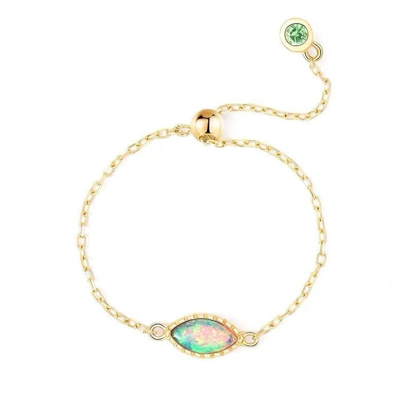 Gold bracelet with opal and green gemstone on a white background