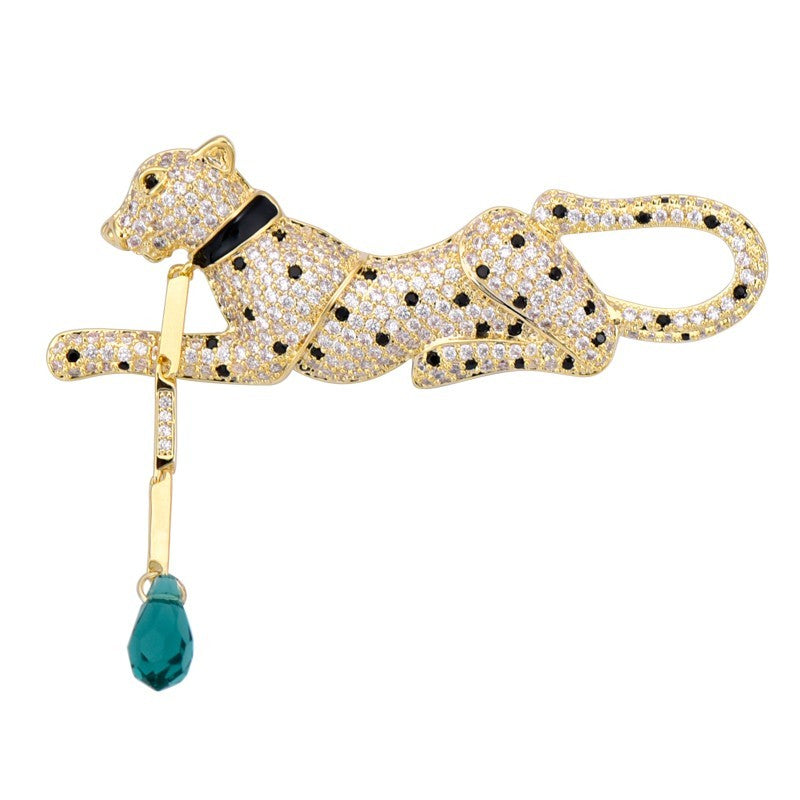 Gold panther brooch with black accents and a blue teardrop pendant on a white background