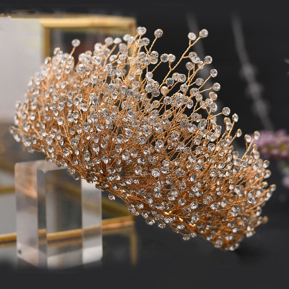Gold decorative headband with crystals on a clear stand against a blurred background