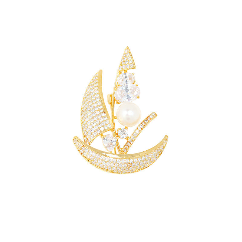 Gold sailboat brooch with pearls and crystals on a white background