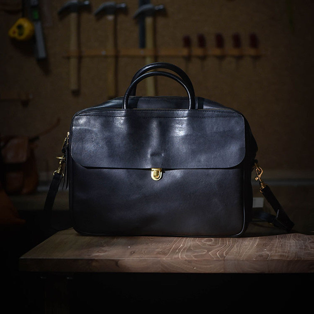 Black leather bag on a wooden surface with tools in the background