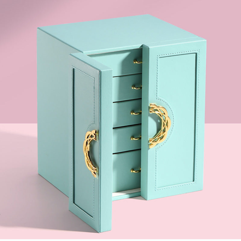 Turquoise jewelry box with gold handles on a pink background