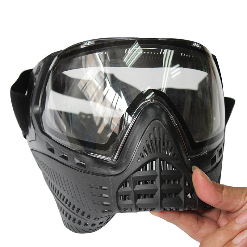 Black tactical mask with clear visor held by a hand on a white background