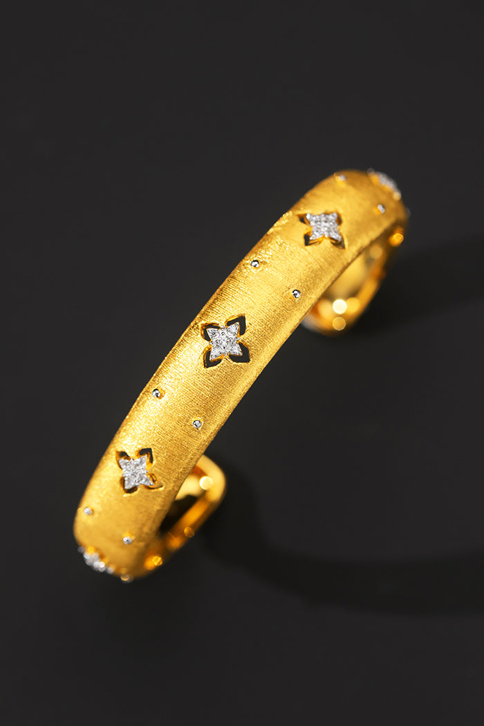 Gold ring with star-shaped diamond cutouts on a black background