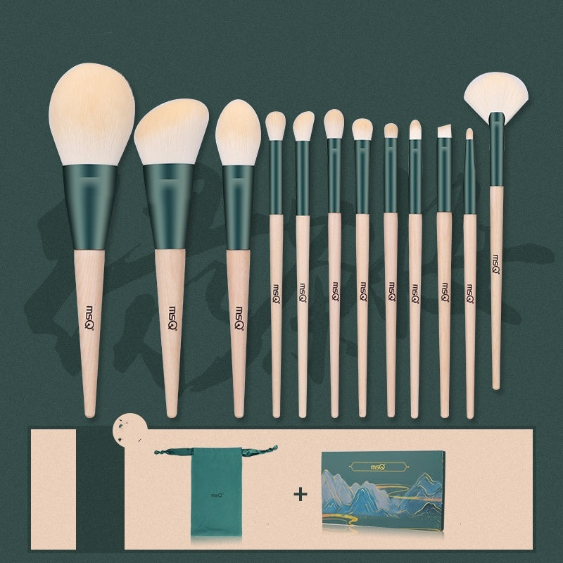 Set of makeup brushes with green and beige handles on a dark green background