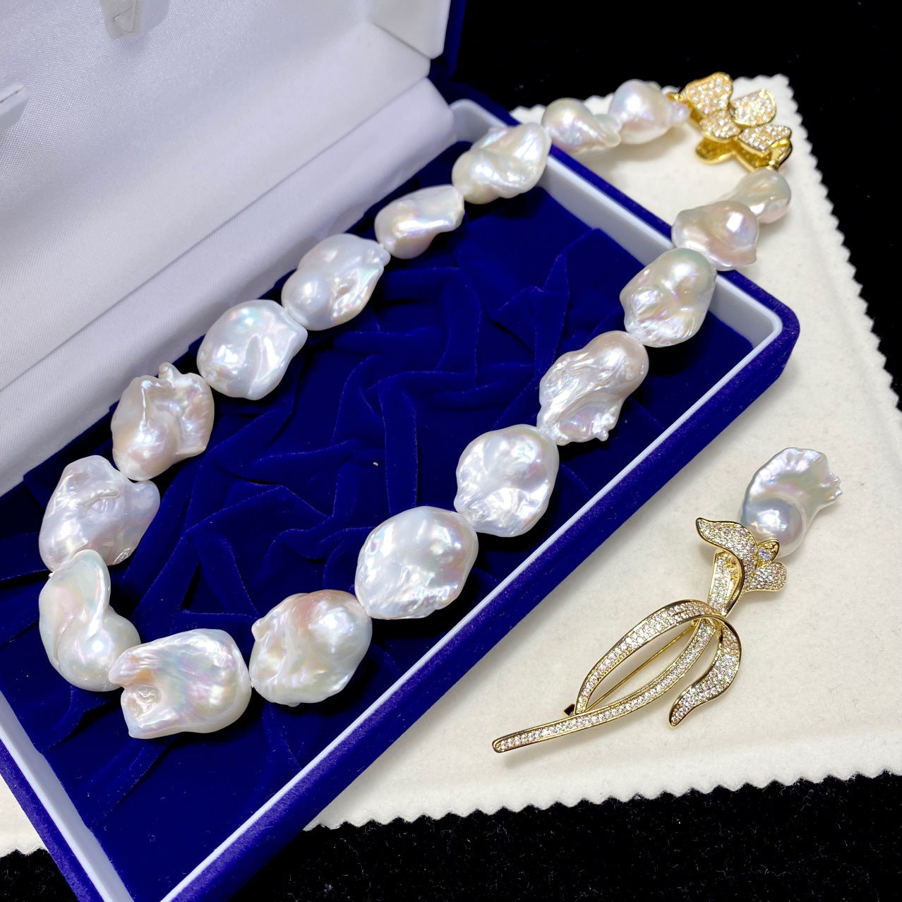 Pearl necklace on a blue cushion with a gold brooch on a white background