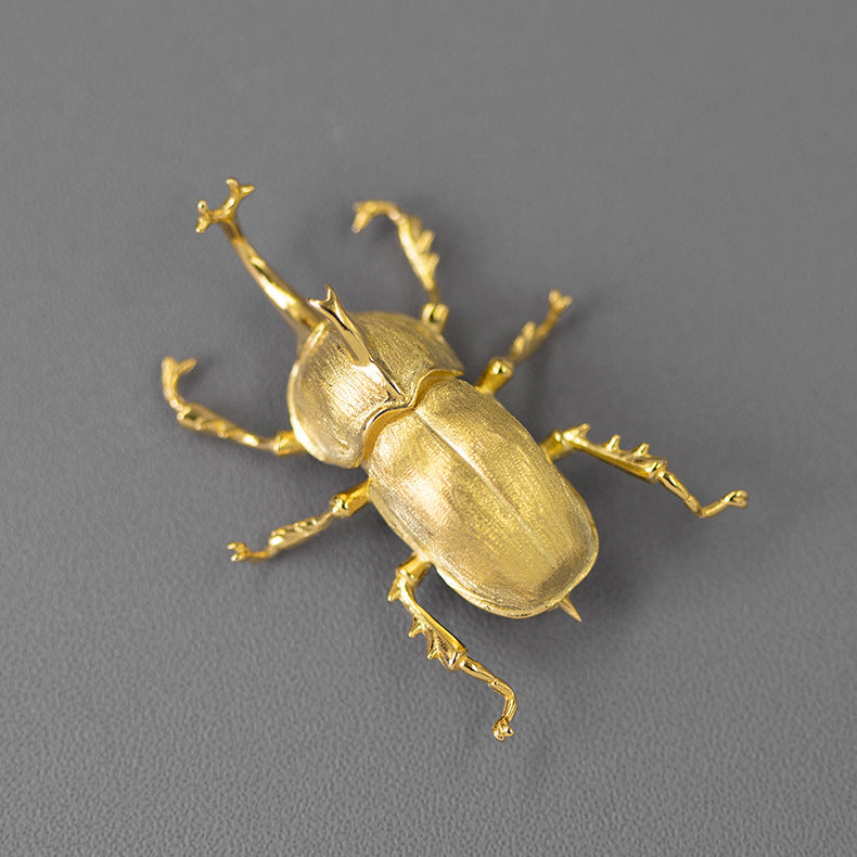 Gold beetle figurine on a gray background