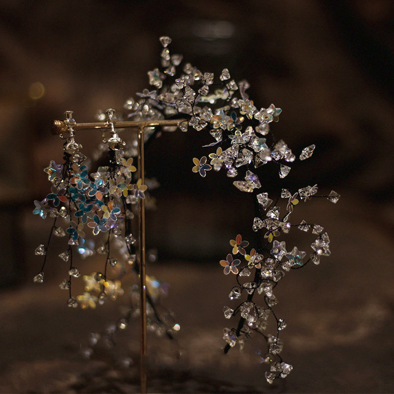Pair of floral earrings with clear and multicolored stones on a dark background