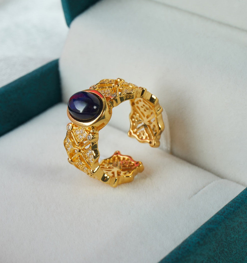 Gold ring with a purple gemstone on a white cushion
