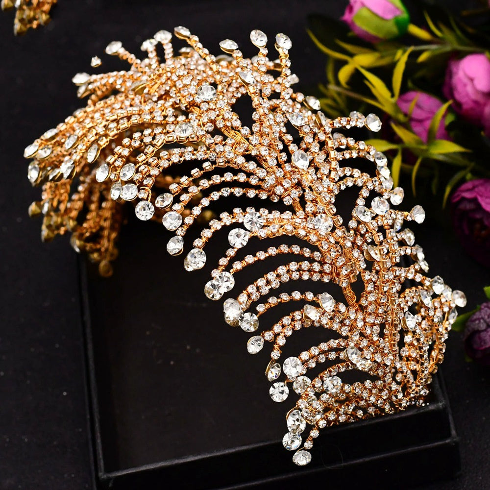 Gold and crystal decorative leaf on a black stand with flowers in the background