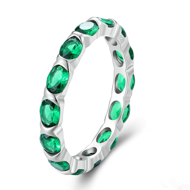 Silver ring with green gemstones on a white background