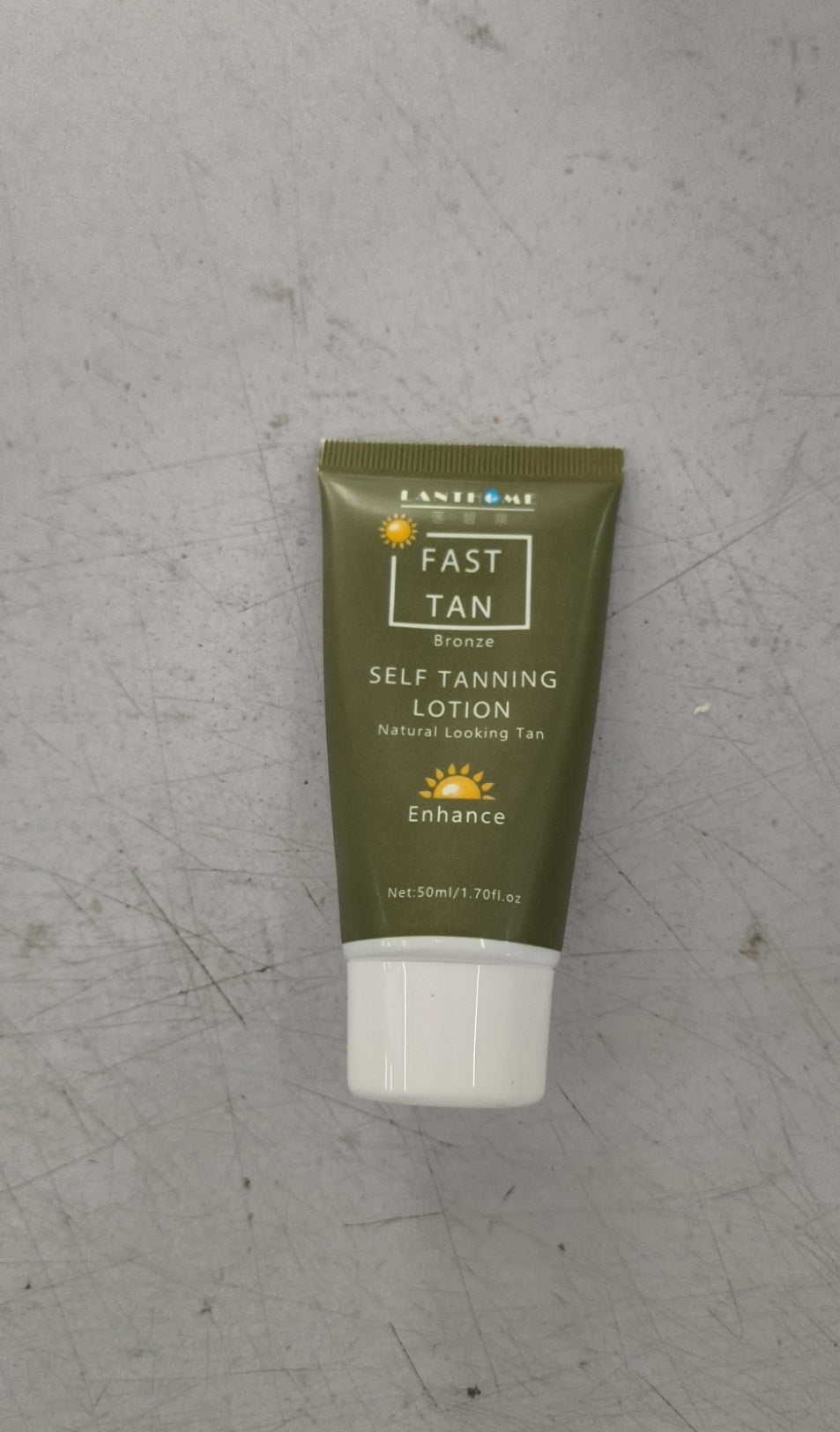 Green tube of self-tanning lotion on a gray surface